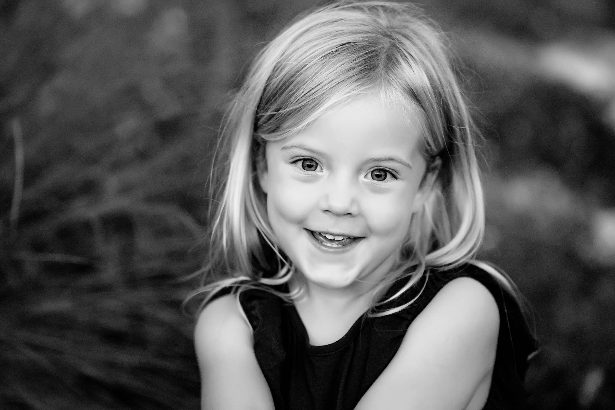 Fun black and white portrait of a little girl smiling and crossing her arms