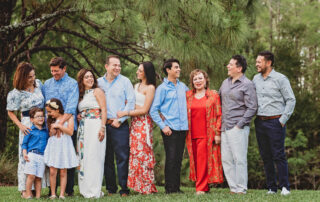 An extended family wearing shades of blue and coral, posing for family photos in Fort Myers, FL
