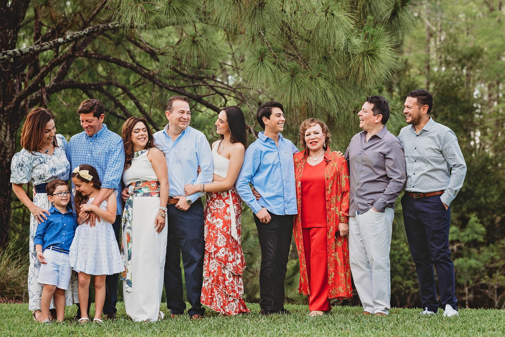 An extended family wearing shades of blue and coral, posing for family photos in Fort Myers, FL