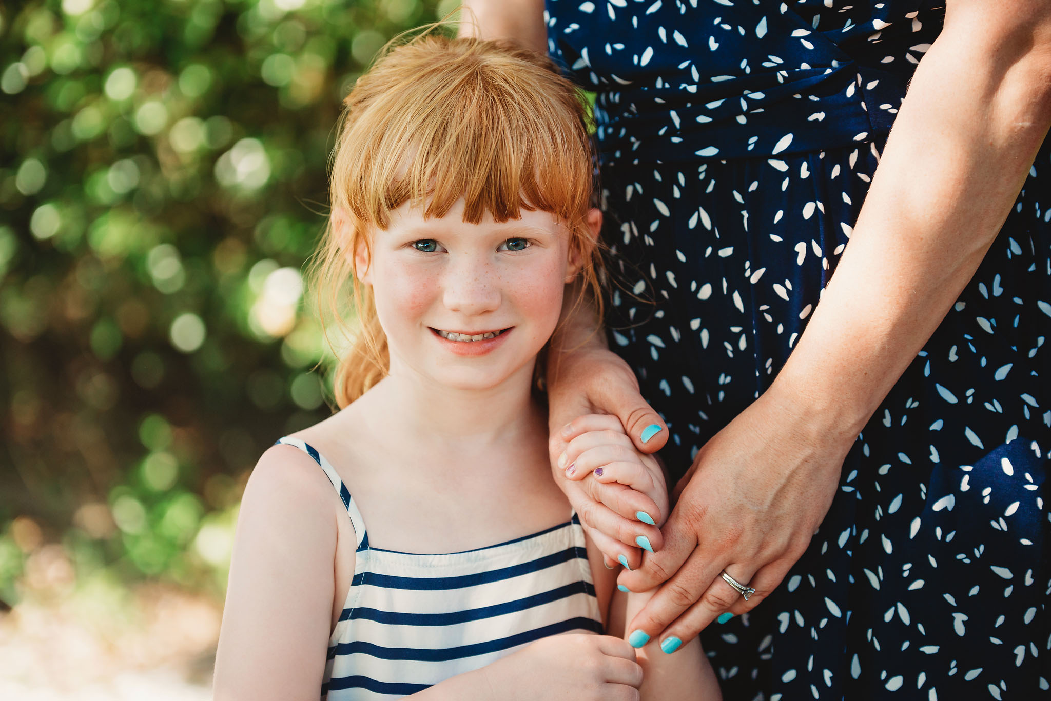 Sweet little red haired girl holds her mothers hand in a photo session for her family in fort myers, Florida