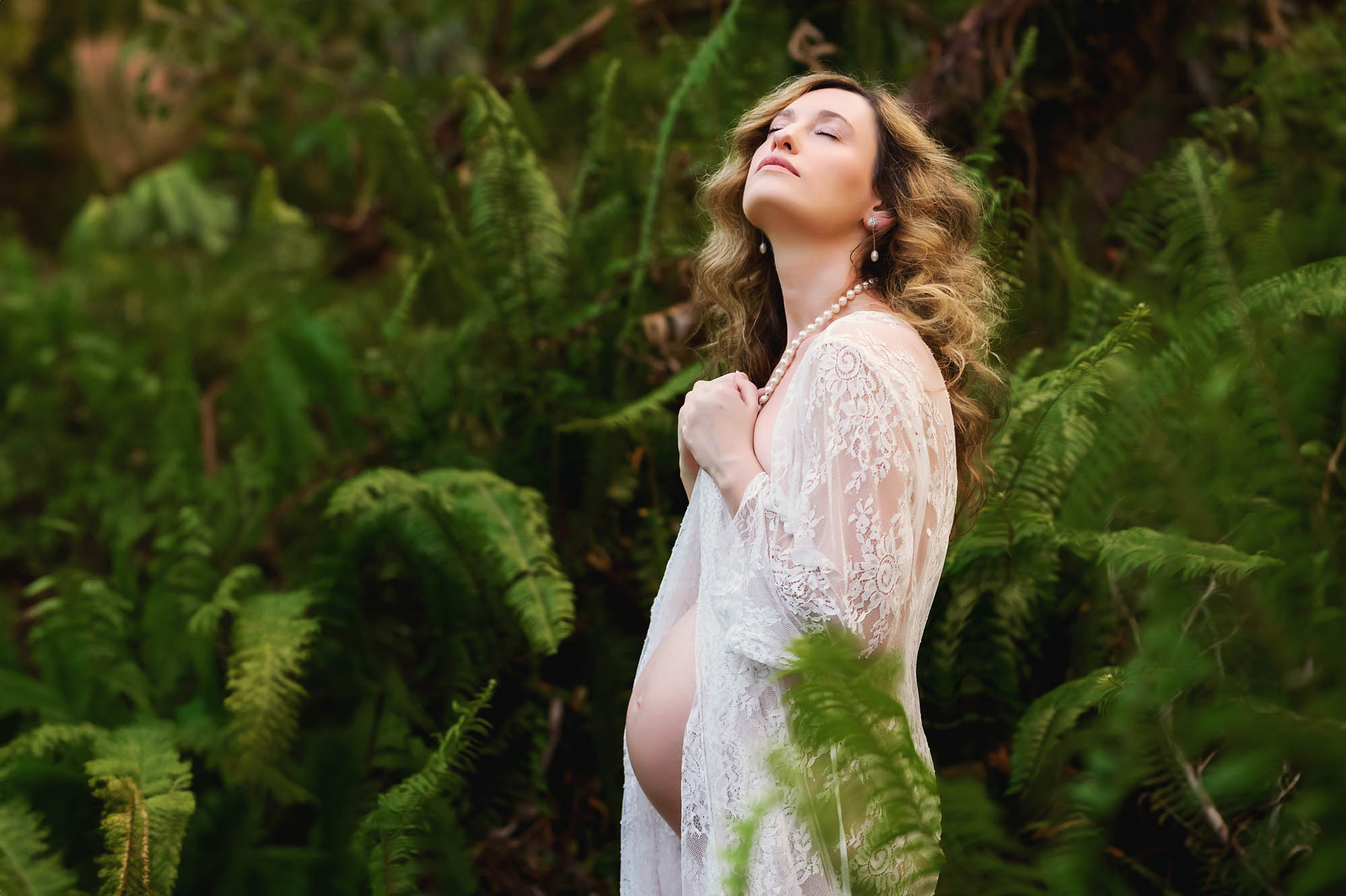 Peaceful pregnant woman posing amongst the green ferns in Fort Myers, Florida