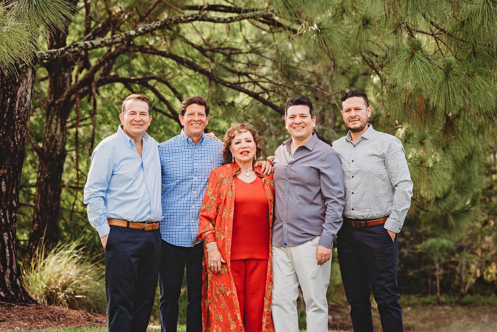 A mom and her adult sons pose for family photos wearing blue and coral.